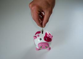hand pushing coin in Piggy Bank