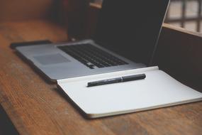 laptop and notebook with pen on the table