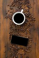 cup of coffee, smartphone and spilled coffee grains on the table