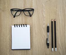 Pen, pencils, notepad and Glasses on the wooden desk