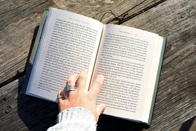 girl's hand with rings on her fingers on an open book