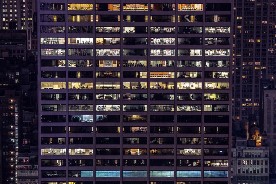 Buildings with the colorful lights inside the rooms, among the other buildings in the city, at the night