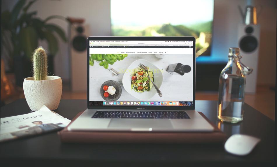 laptop on desktop next to green plant