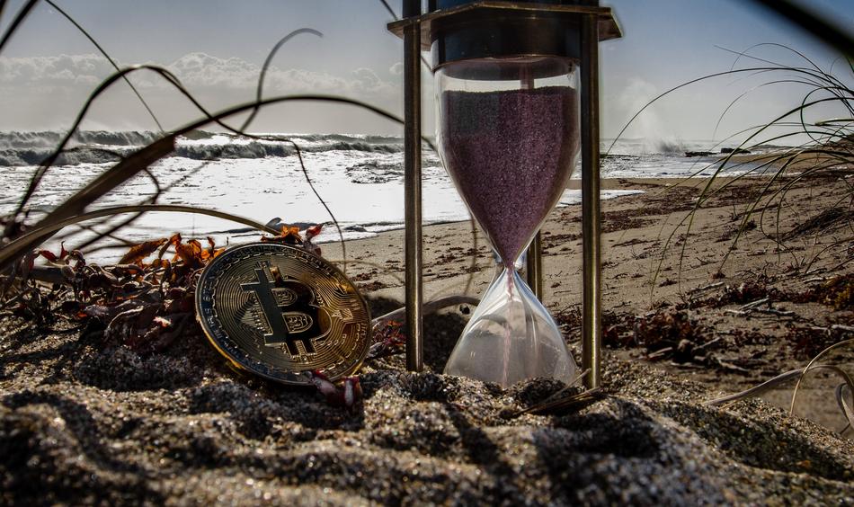 cryptocurrency and hourglass on the beach