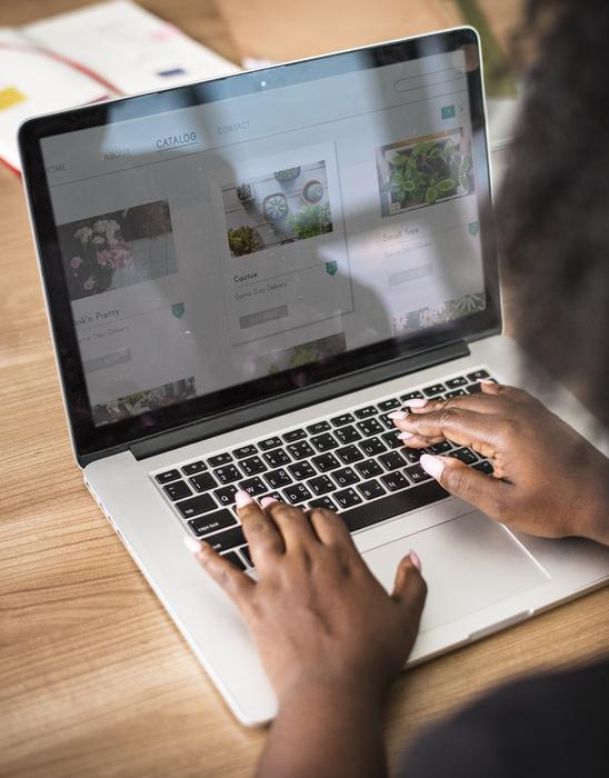 Woman, using laptop with the shiny screen, on the wooden desk