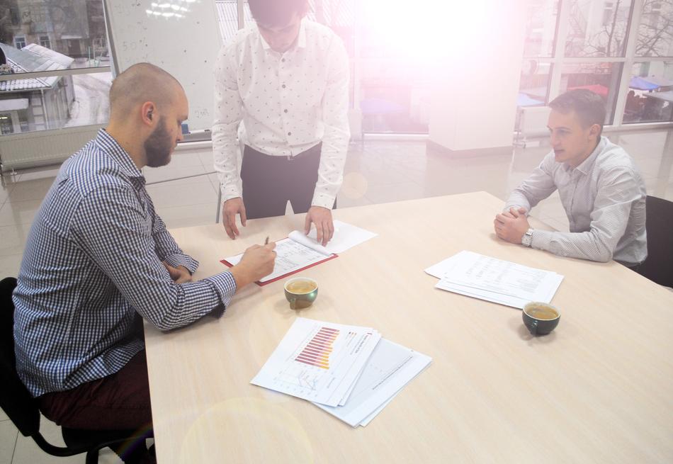 People signing papers at the desk in the office