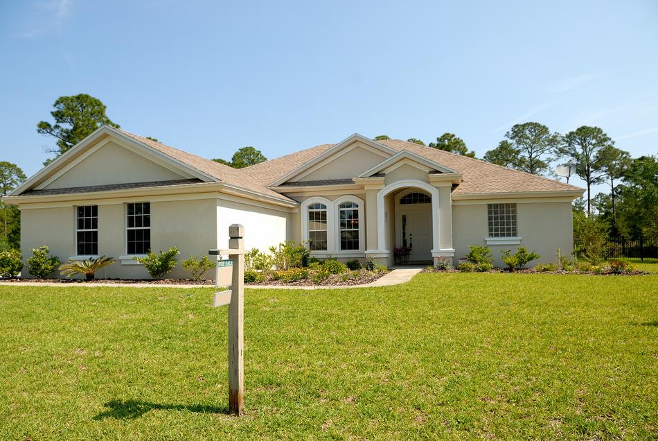 Home in light, with the sign and colorful garden in Florida, under the blue sky, with clouds