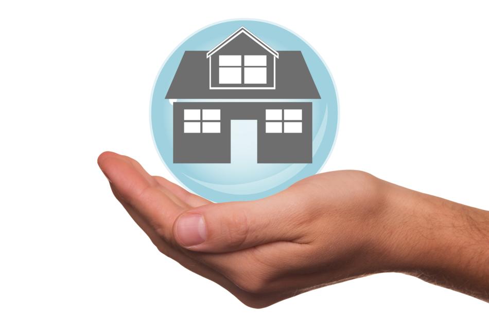 Round icon of home insurance on the hand at white background