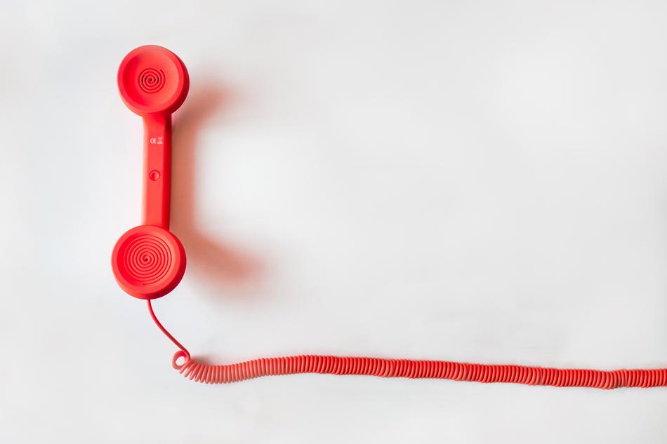 Beautiful, retro, red phone with the wire, on white surface