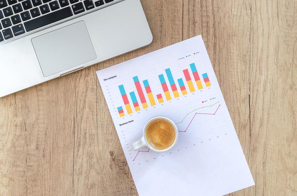 Coffee on the finance graph near the laptop on the table