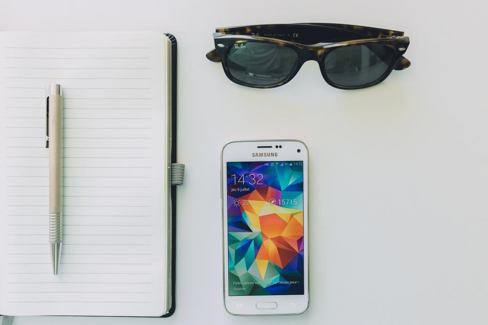 sunglasses and phone and pen and note