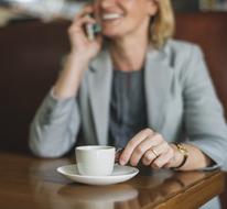 American Blonde woman with coffee cup talking on phone