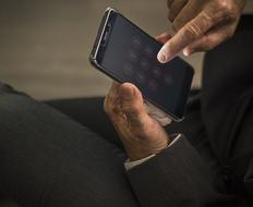 black smartphone in the hands of an elderly man