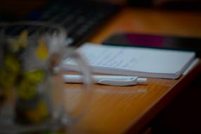 Close-up of the office table, with the pen, notebook, cup and other stuff
