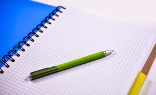 spiral notebook with green pen