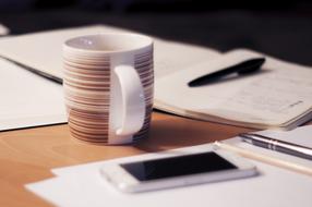 smartphone, mug and papers on Office desk