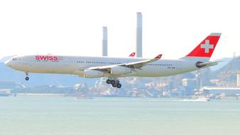 Airplane of swiss airlines in flight above water at city, china, Hongkong