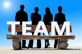 Black people silhouettes near the wooden bench with white "TEAM" sign, at blue sky with Sun on background