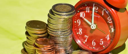 red alarm clock and stack of coins