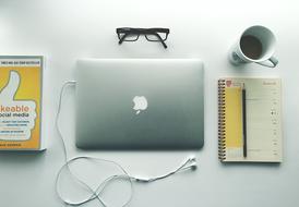 books, closed laptop Computer, earphones, glasses and cup on desk