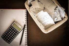 Calculator on notepad and Bills on desk