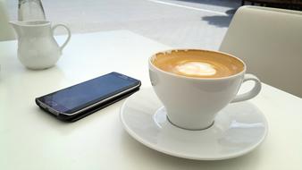 smartphone and a cup of coffee on a table in a restaurant