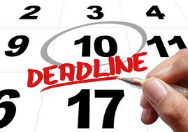 deadline, hand with pen above red word on calendar