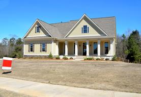 Colorful home for sale, with columns, among the colorful trees, at blue sky on background in Georgia, USA