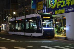 Tram, with the lights, near the building, with the colorful signs, at the night, in Japan