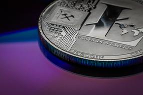 Close-up of the shiny metal coin with the sign of "Litecoin", at colorful background, clipart