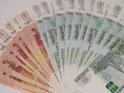Fan of orange and green Russian banknotes on a white surface