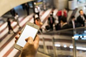 iphone 5 in the hand of a man descending the escalator