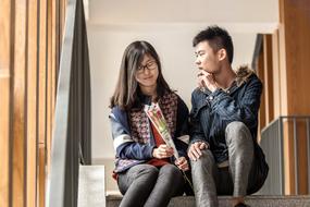 loving asian students sit on the steps