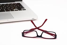 glasses and laptop keyboard on white table