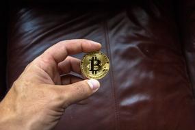 Hand holding gold coin with Bitcoin sign