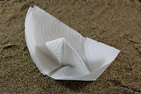 paper boat lies on the sand close-up
