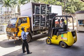 Yellow car and forklift near a warehouse