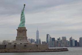 statue of liberty in view of City at cloudy day, usa, nyc