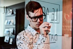 young man writing with Marker on glass