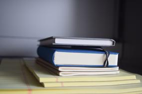 Colorful books and notepad, near the white wall in light