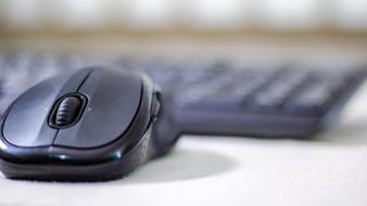 Close-up of a black mouse, at blurred background with black keyboard