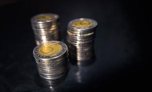 Three stacks of the shiny and colorful Polish Zloty coins, at black background