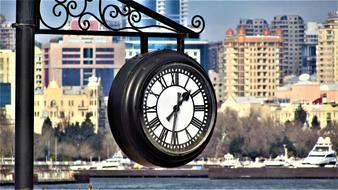 clock on pole in view of coastal city