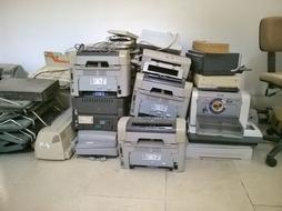 pile of Old Printers on floor at wall