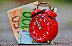 red alarm clock and two euro banknotes