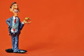 figurine of a man with a piggy bank in his hand on an orange background