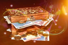 banknotes and coins in a wooden box in a blurred background