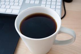 Coffee in Cup near Keyboard close-up