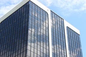 Top of the shiny glass building, at blue sky with white clouds