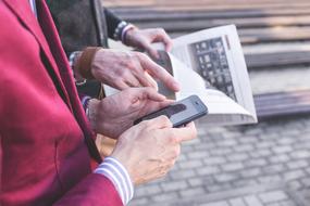 People with the newspaper and smartphone, in the hands